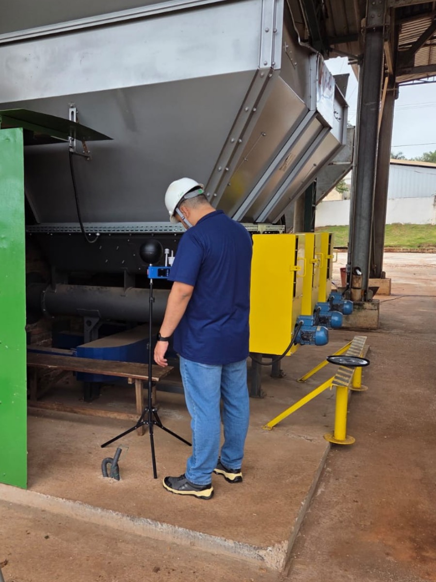 Avaliação ocupacional de calor (NHO-06): técnico com medidor em tripé junto a maquinário industrial