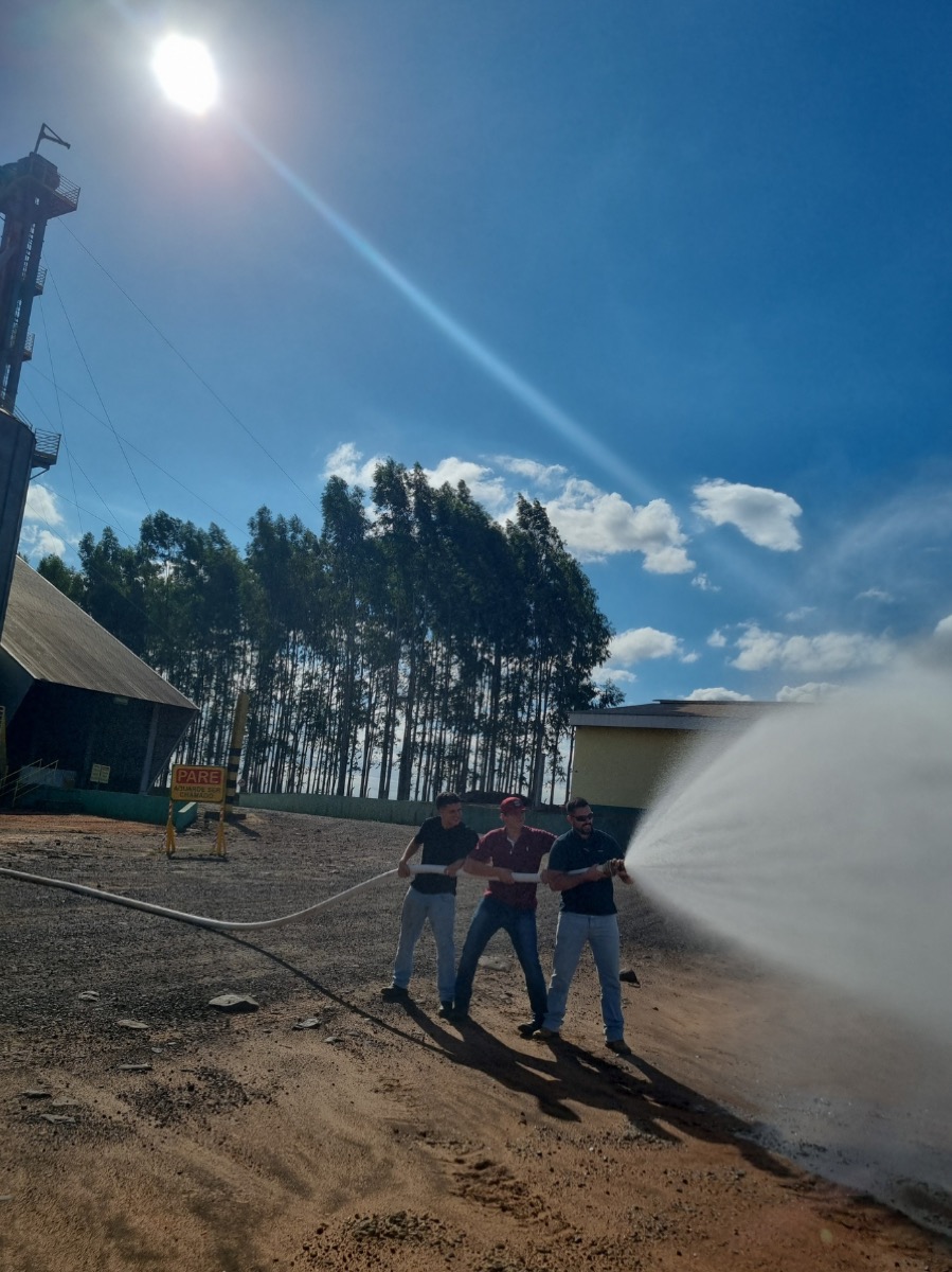 Treinamento de brigada de incêndio (NR-23): participantes manejando mangueira em área externa
